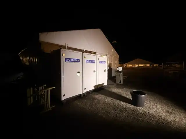 Cabines WC Clean éclairées de nuit devant un chapiteau