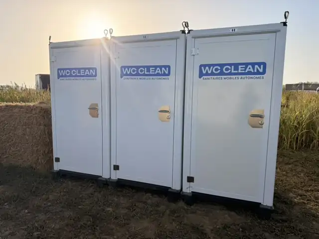 Toilettes mobiles Premium : trois cabines WC Clean alignées au coucher du soleil
