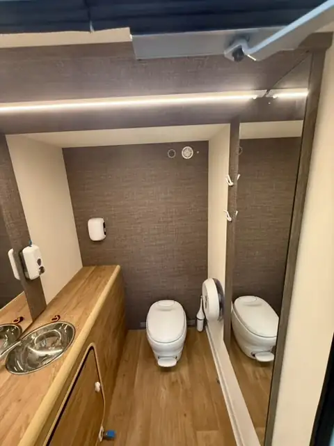 Sanitaires autonomes Prestige, intérieur : plan vasque en bois, WC et éclairage soigné